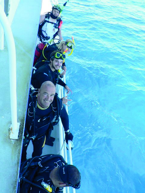 Scuba divers lining up on MV SeaEstas starboard side getting ready to jump in the water